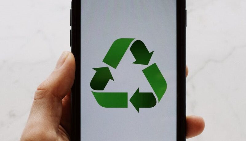 Hand holding phone with recycling sign