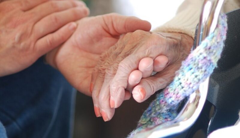 Young hand holding old woman's hand